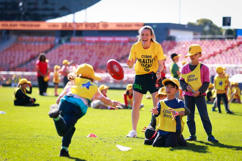 kids playing on the field with an AFL player