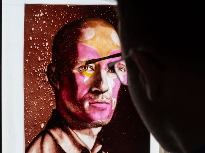 Christian Rex van Minnen painting a pink and yellow mask onto a monotype portrait
