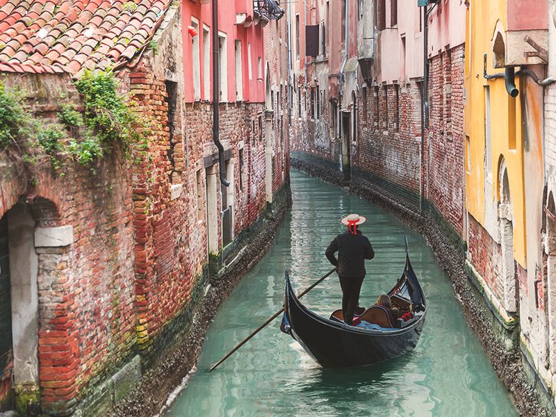 gondolier riding on gondala in canal in venice italy