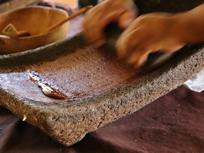 person making mayan chocolate on traditional board