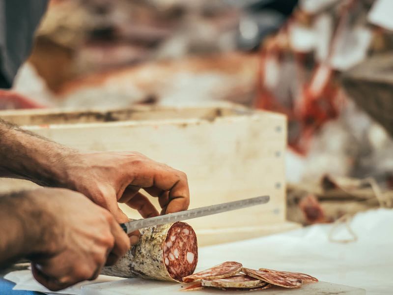 close up of man cutting salami
