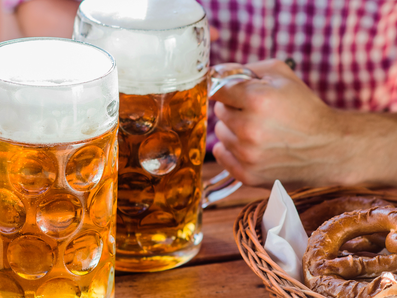 two steins of german beer and a basket of pretzels