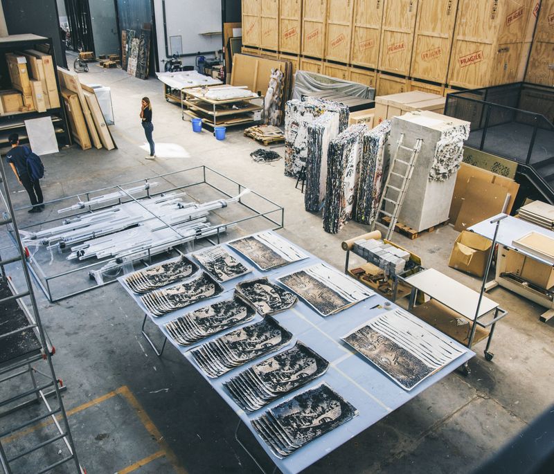 looking down on studio floor filled with various storage containers and boxes, works of art and tools