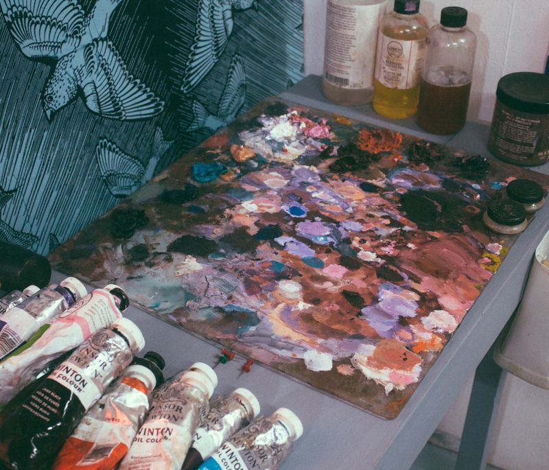 large paint palette on a table next to various tubes of oil paints