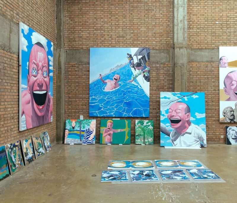 view of artist's studio with dozens of paintings of varying sizes hung up and propped against walls
