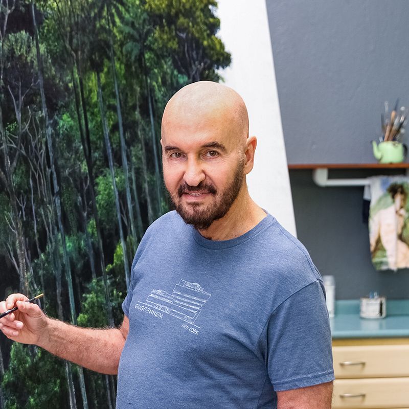 Tomas Sanchez smiling and holding a paintbrush