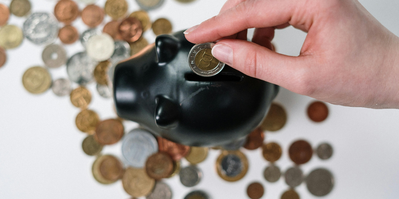 Coints being placed inside a piggy bank