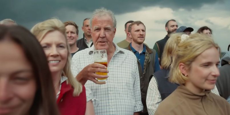 Jeremy Clarkson holding a glass of Hawkstone Lager in the choir of farmers