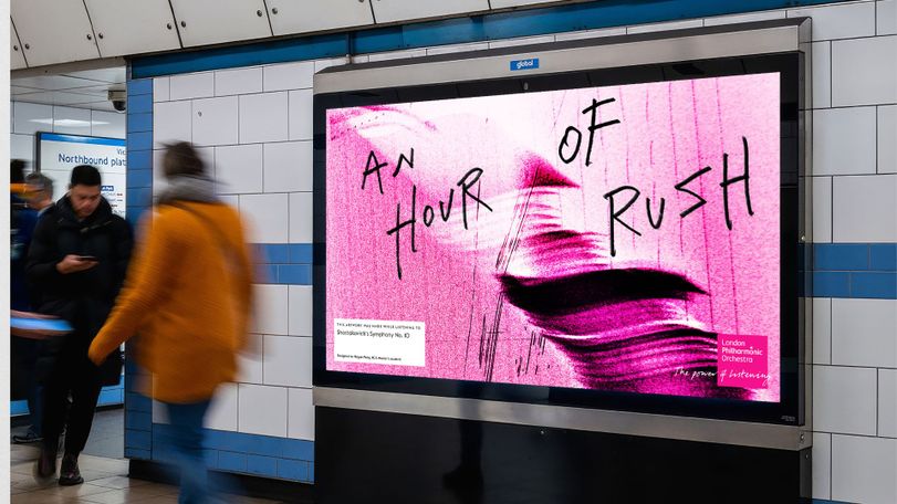 Blurry commuters pass a digital advertisement in a subway station reading "An Hour of Rush" with a pink abstract background.