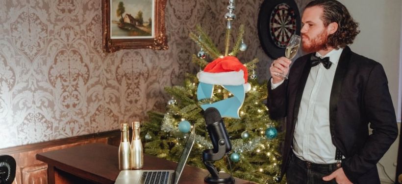 Man drinking champagne in front of Christmas tree in the pub