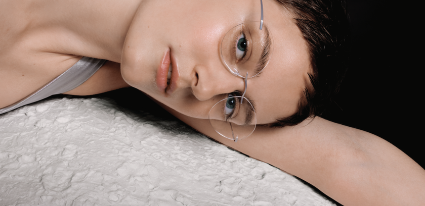 Femme portant une TMA sans monture argentée - L'Icône allongée sur une surface semblable à la lune