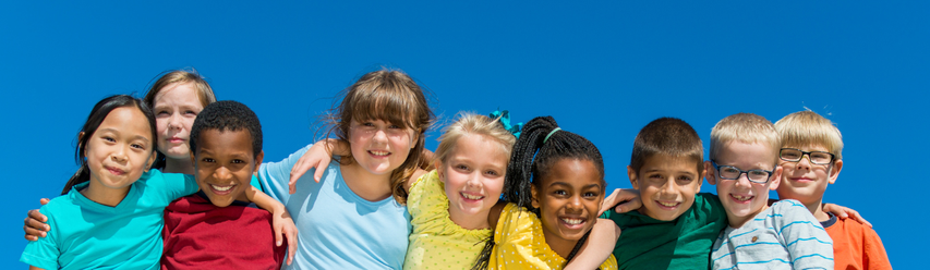 A diverse group of nine smiling children standing close together under a bright blue sky.