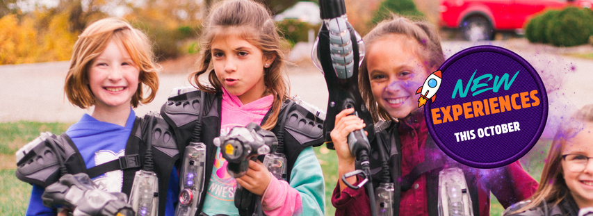 Three kids smiling and holding laser tag equipment outdoors, with a badge saying "New Experiences This October."