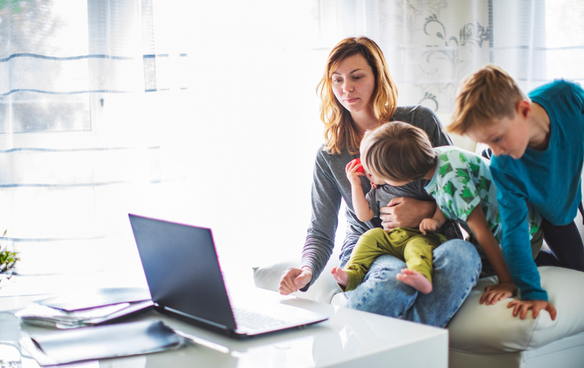 mum using laptop while kids are being energetic