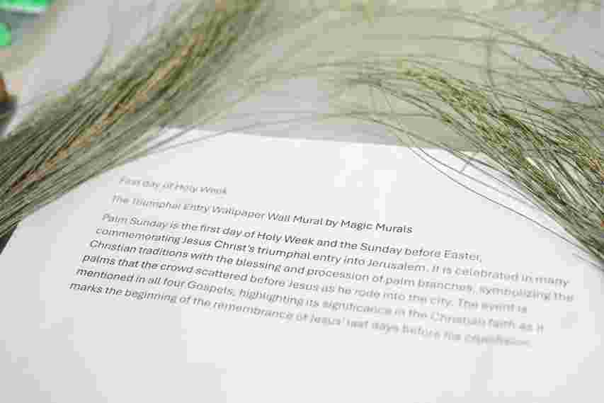 A close-up of a document describing Palm Sunday overlaid with decorative palm branches on a table.
