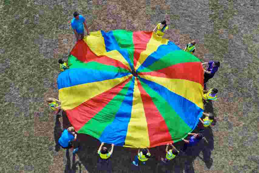 JAG staff and children playing parachute games on a field