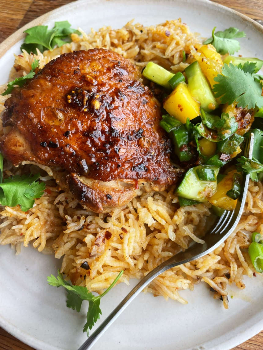 chili crisp chicken thighs with mango salsa and rice on a plate