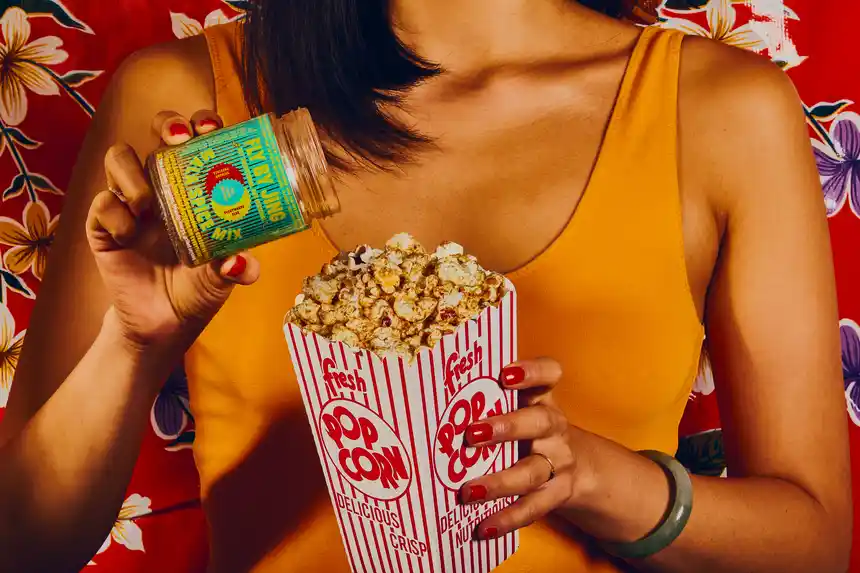 Woman pouring Mala Spice Mix onto a box of popcorn