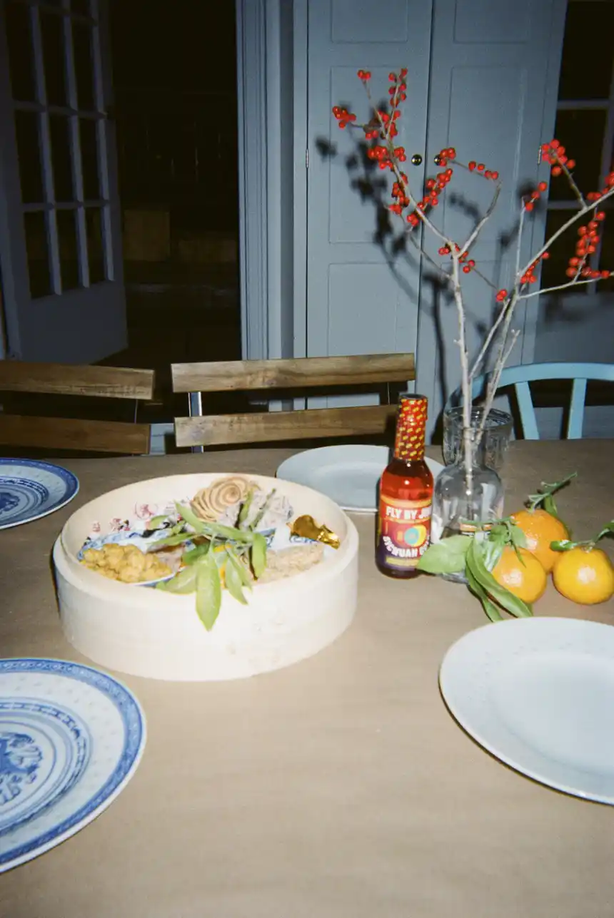 a tablescape filled with oranges, a bottle of Sichuan Gold, and festive decor