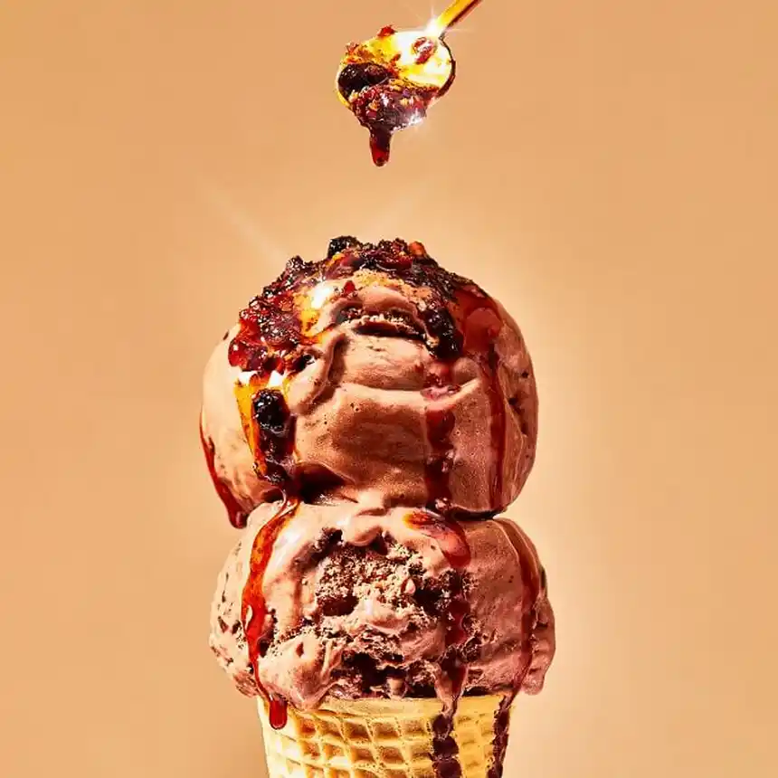 Chocolate ice cream cone on a yellow background with Fly By Jing Sauce on top
