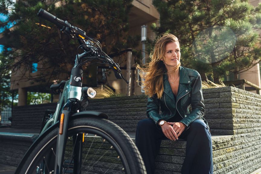 Kvinde sidder ved væggen med Sparta e-bike d-BURST