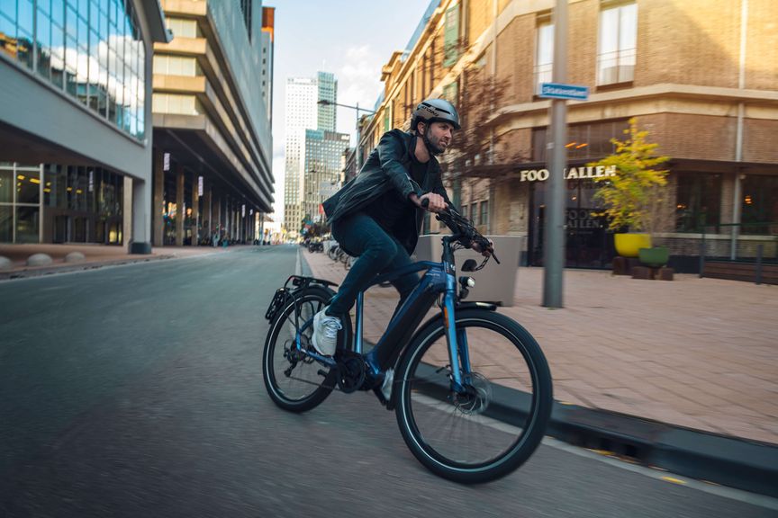 Man met helm op e-bike rijdt in bocht in de stad