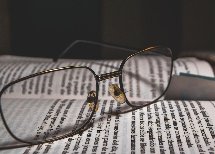 Home care packages- Cropped photo of reading glasses sitting on an open book with book mark