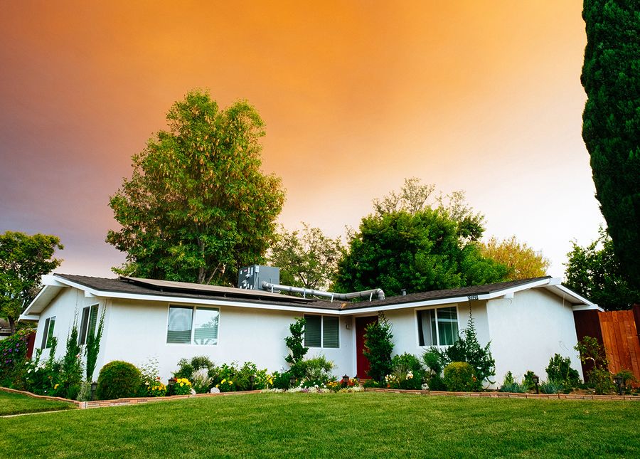 Safety at home- Real estate photo of a white house and green lawn with orange sky
