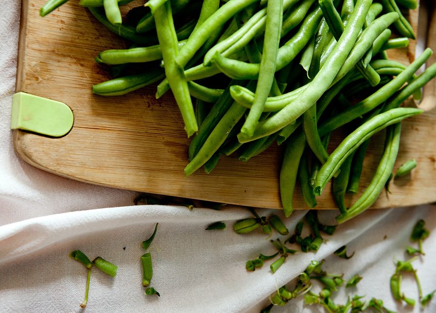 Home care package providers- cropped photo of green beans on a wooden chopping board and white cloth underneath