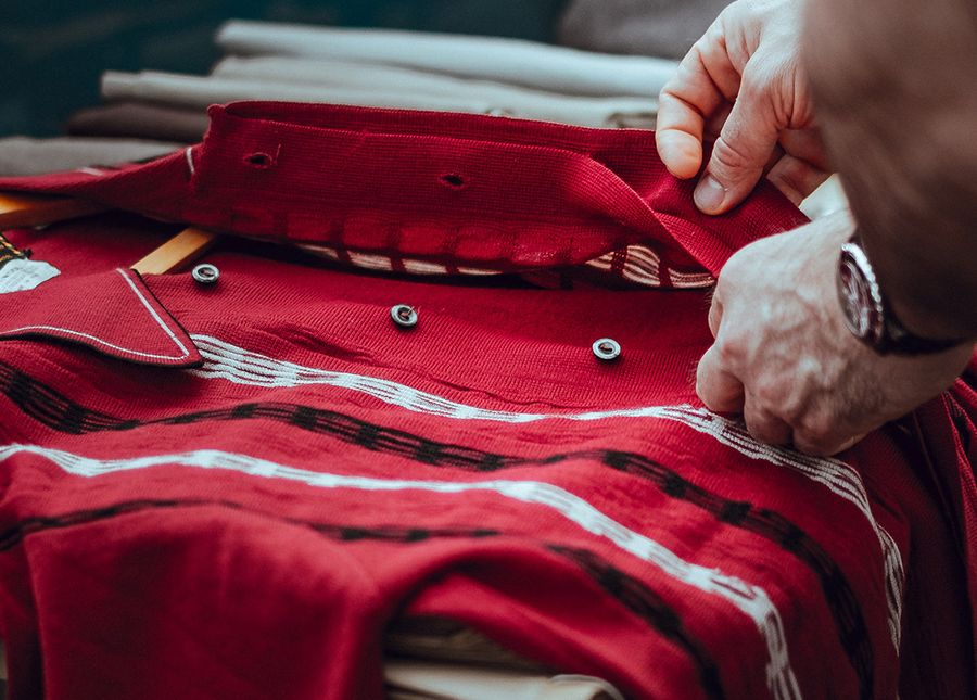 Home care package options- Close up photo of older hands buttoning a red shirt on a table