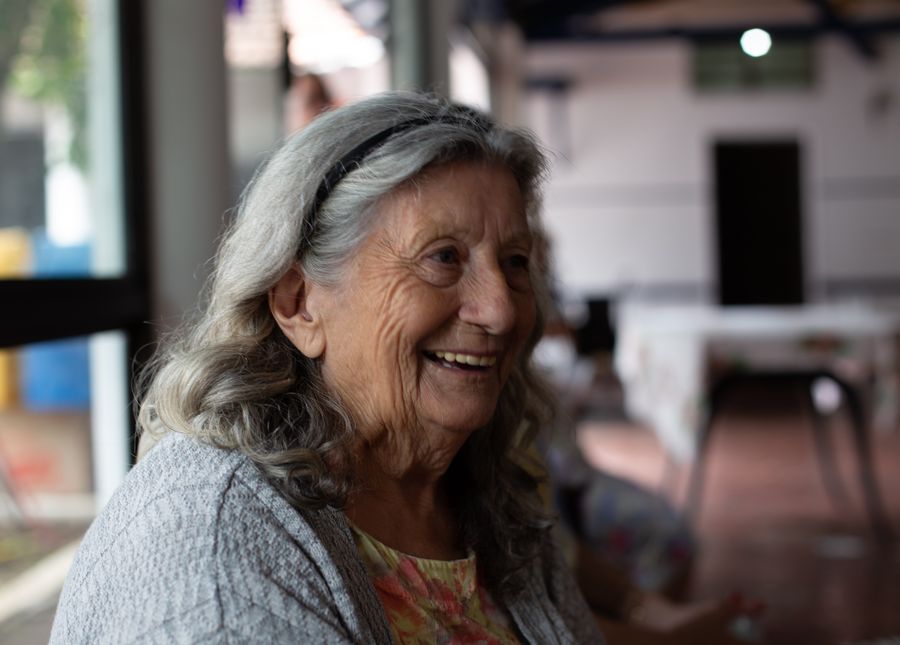 Types of respite- Photo of an older lady with grey shoulder length hair and black head band smiling.