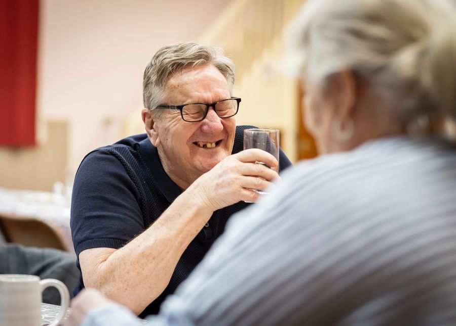 Photo of an older man smiling holding a glass of water going through the steps to take to enter residential aged care