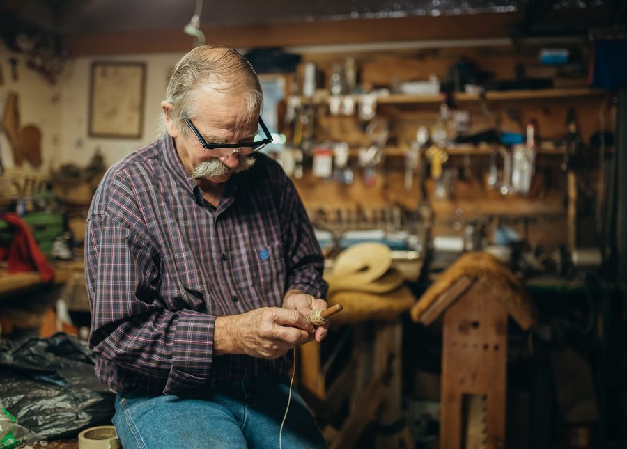 Dementia quality of life- Photo of an older man balding with grey hair a moustache and glasses working on something with his hands in a workshop or shed