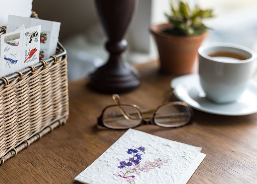 Eligibility for residential aged care. Photo of glasses, greeting card, stamps and cup of tea and sauce sitting on a wooden tabler