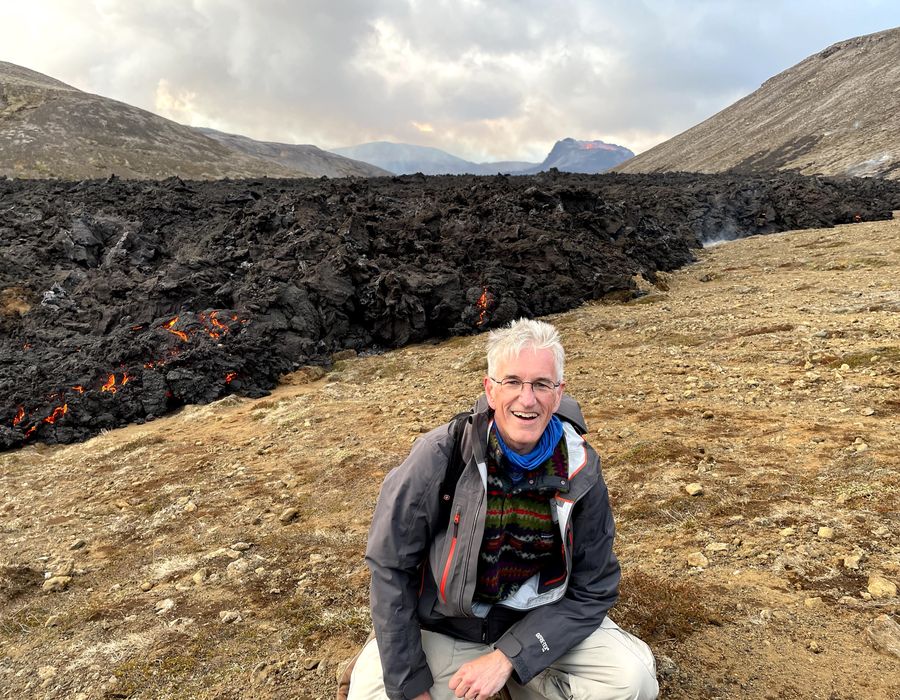 traveler smiling at camera in front of lava from volcano in iceland