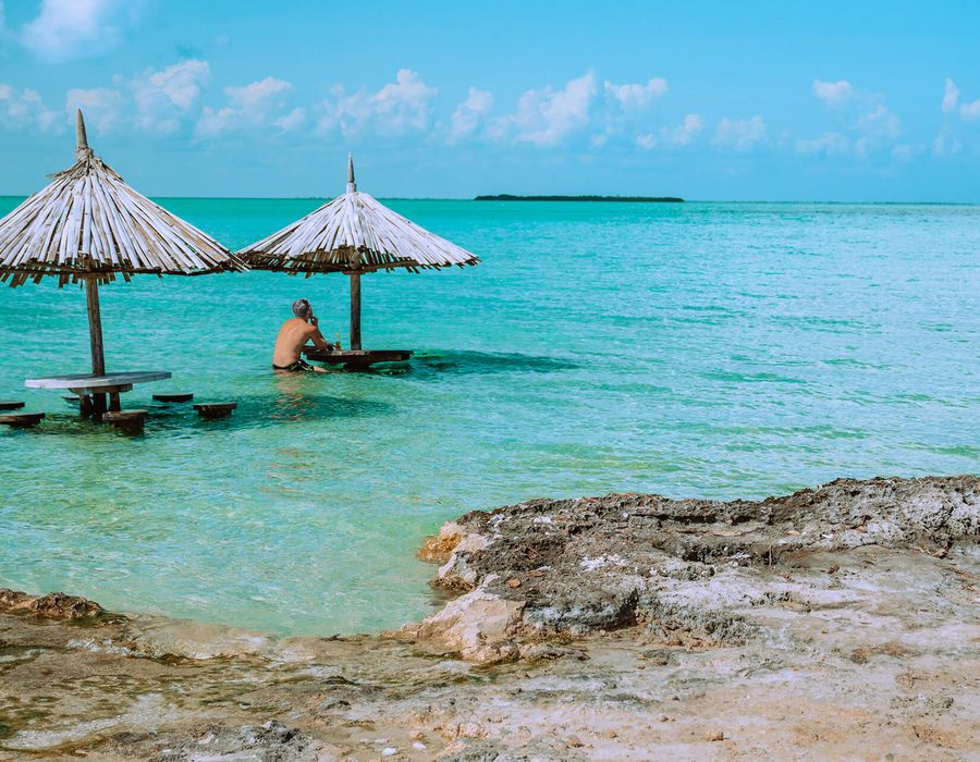 man sitting at a tiki table in the ocean off the coast of Belize