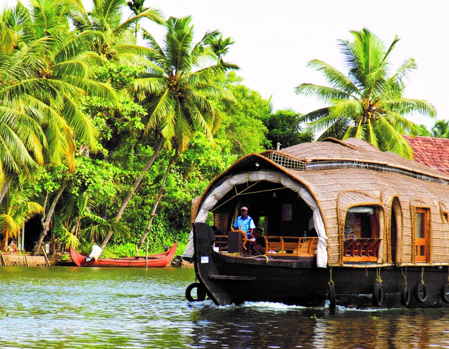 man in blue shirt driving house boat on river in kerala india