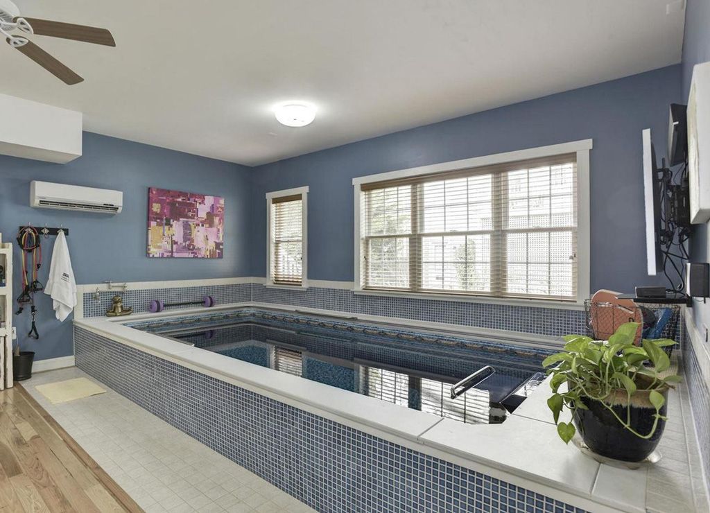 A picture of a sleek indoor pool set-up, with lots of exercise equipment around it.