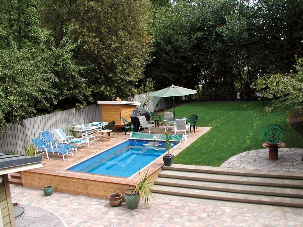 A picture of a pool deck with a partially in-ground swimming pool, tables, chairs, and potted plants.