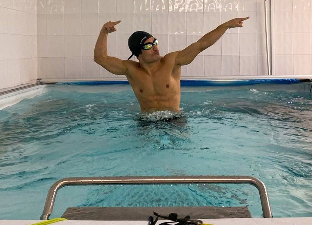 A picture of a man posing in a pool, showing off his muscles. 