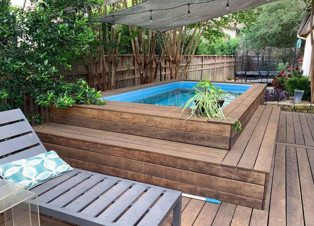 A picture of a pool built semi-above ground on a deck with a lounge chair sitting beside it.