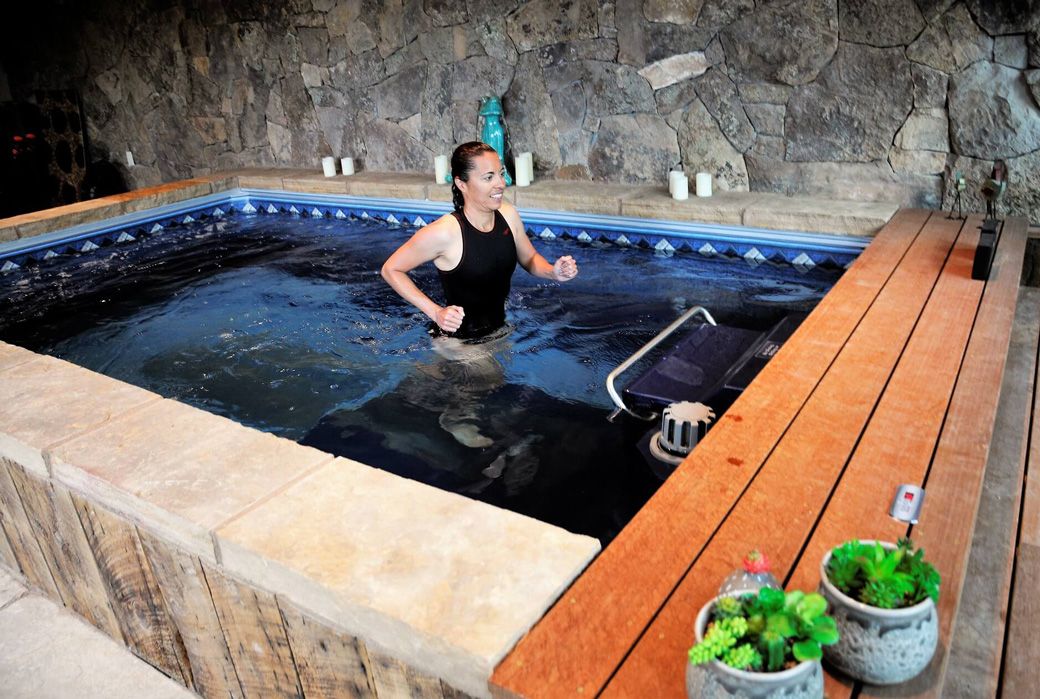 A picture of a woman running on her water treadmill in an enclosed pool. 