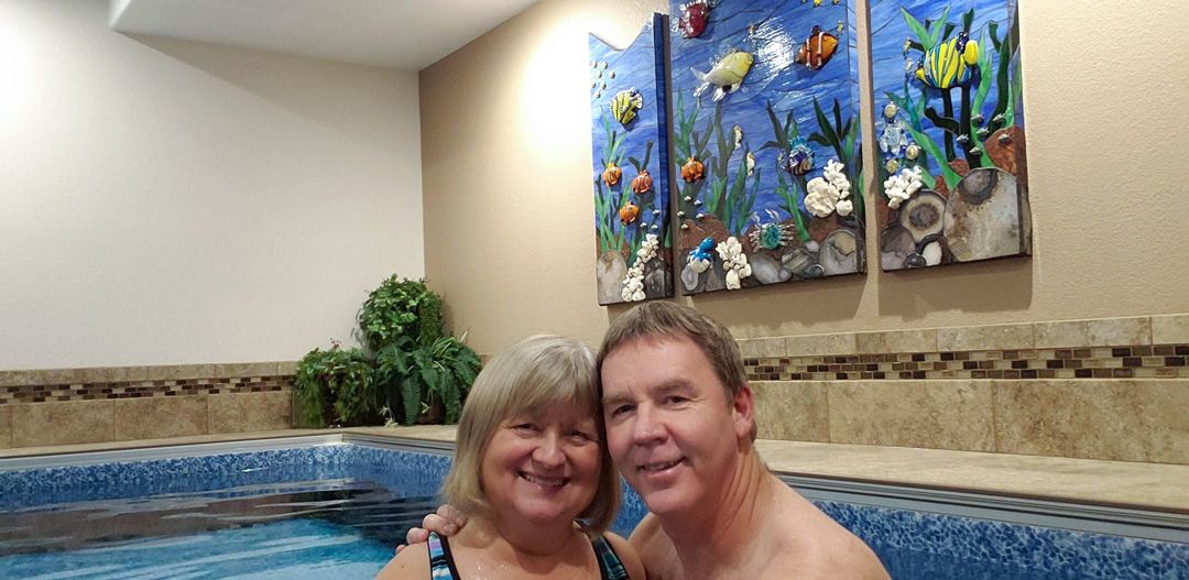 A picture of a man and a woman embracing each other in their pool.