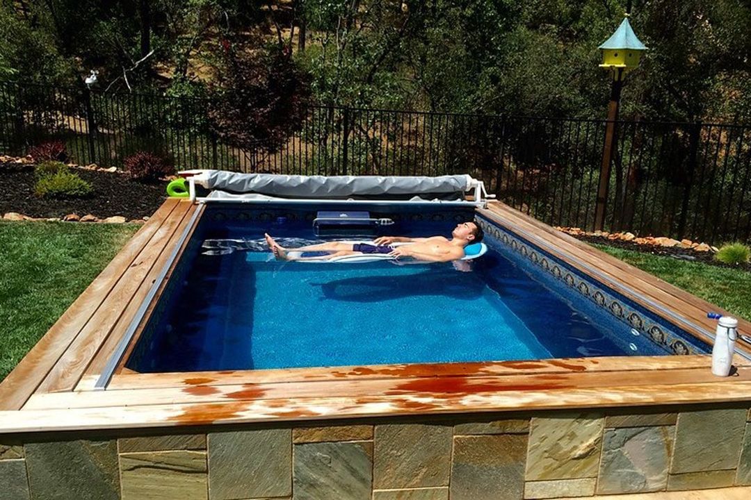 A picture of a man relaxing on a raft in his pool.