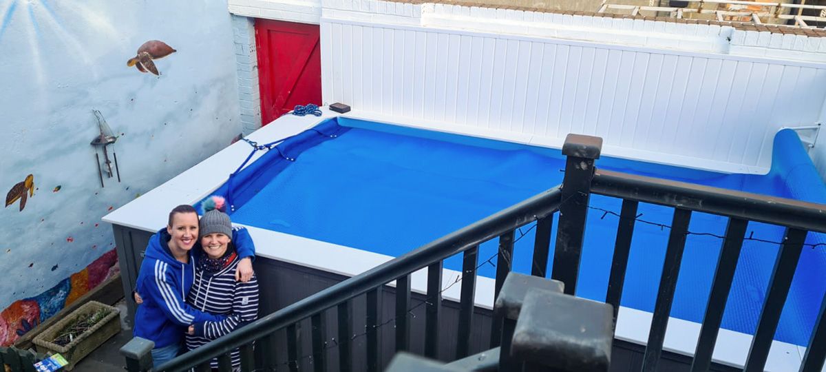 picture of swimming coach Lindsey and her wife by their Endless Pools backyard pool