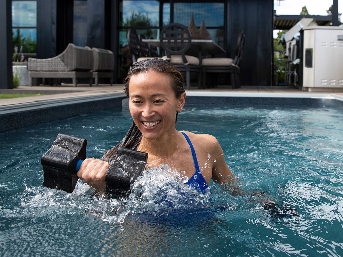 Woman exercising with aquatic dumbbells in pool
