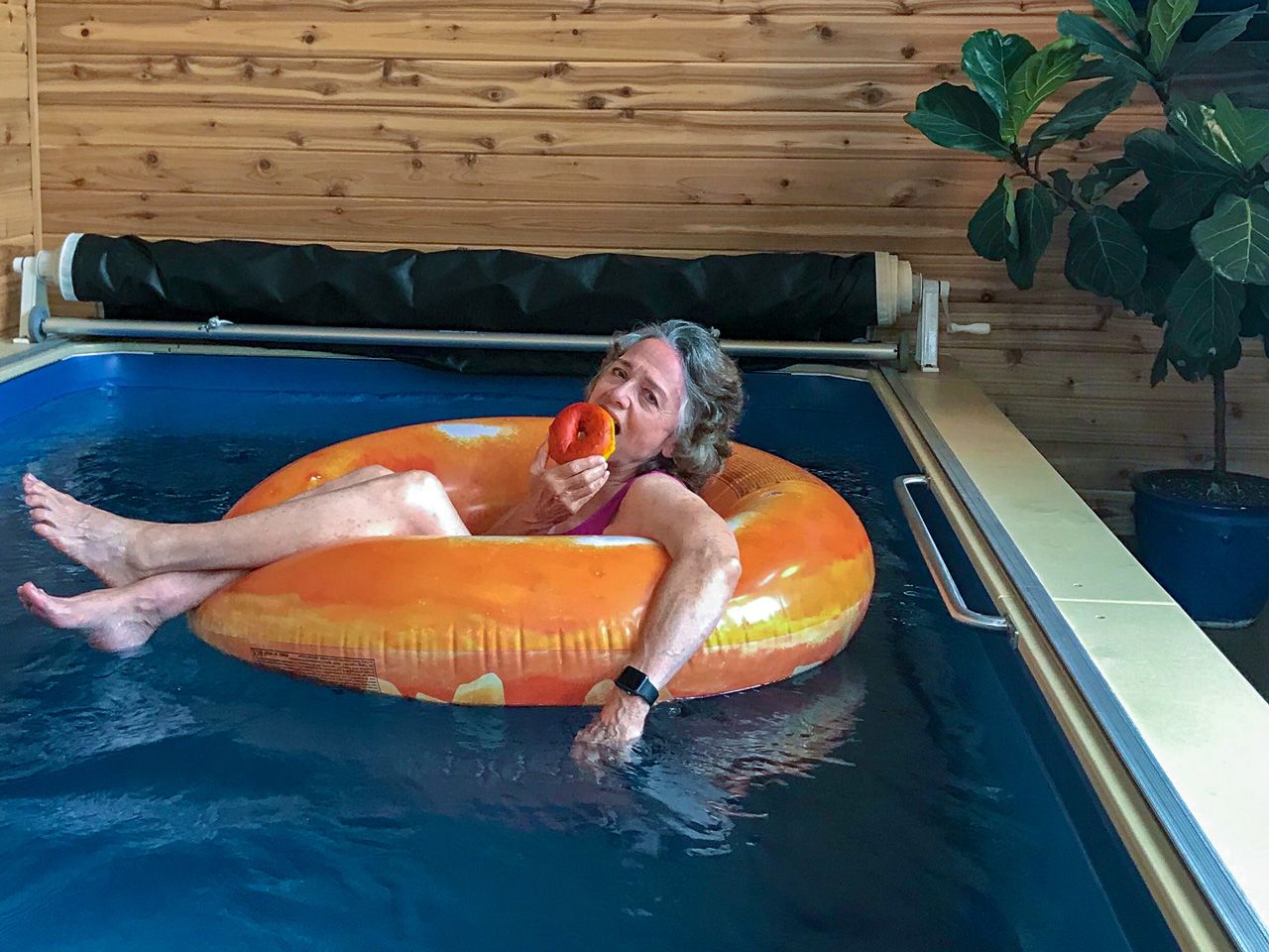 A picture of a woman in a donut innertube, floating in an indoor pool.