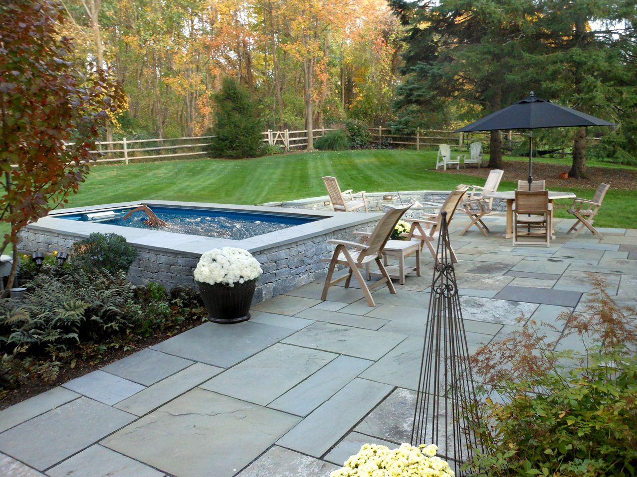 picture of Fall comes early to Connecticut, so you can see the stunning golden leaves as early as September. Better still, you can enjoy the view from this Performance pool, installed partially in-ground for easy access and a lower profile. The pool's stone-gray finishing coordinates with the patio tile for an organic feel. 