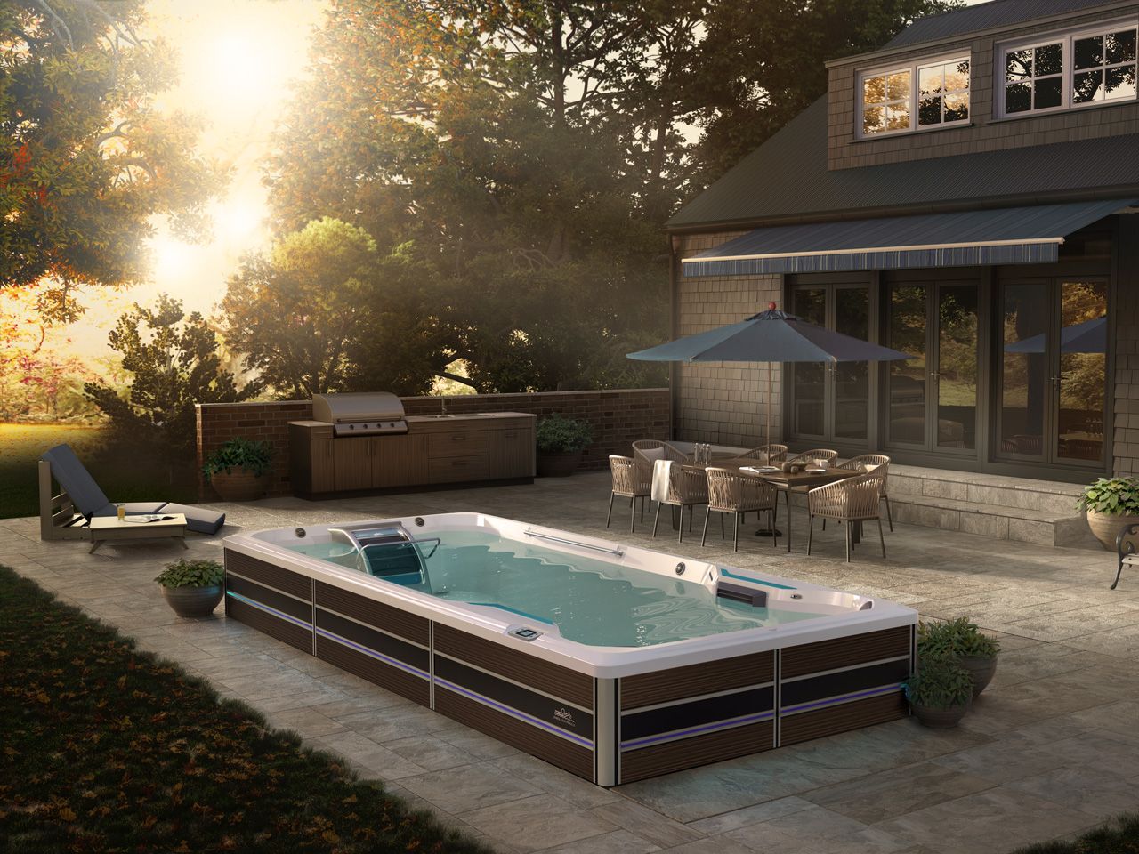 A picture of a swim spa on a beautiful deck, surrounded by furniture and nature as the sun sets through the trees.