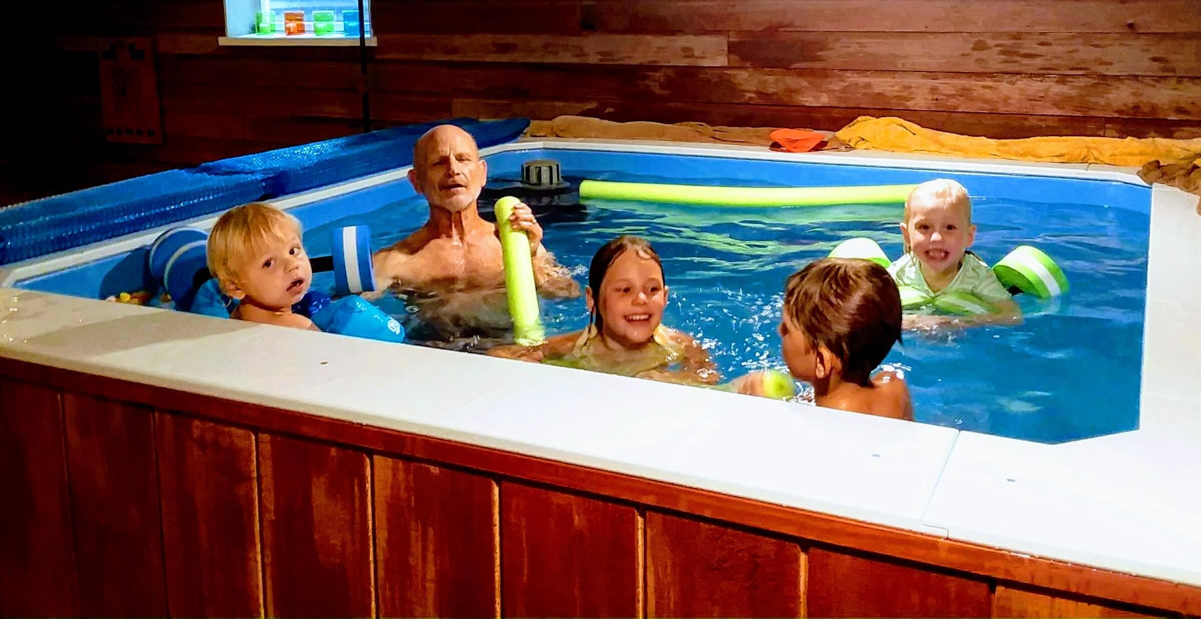 picture of Joan's husband and their grandkids enjoy playtime in her Endless Pools WaterWell therapy pool